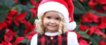 Girl wearing Santa hat standing among flowers